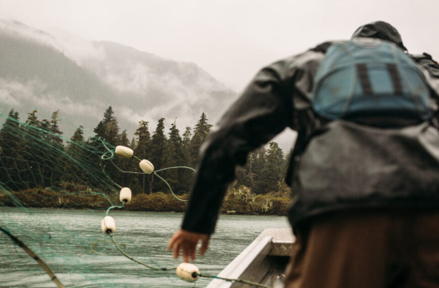 A man with a fishing net on a boat.