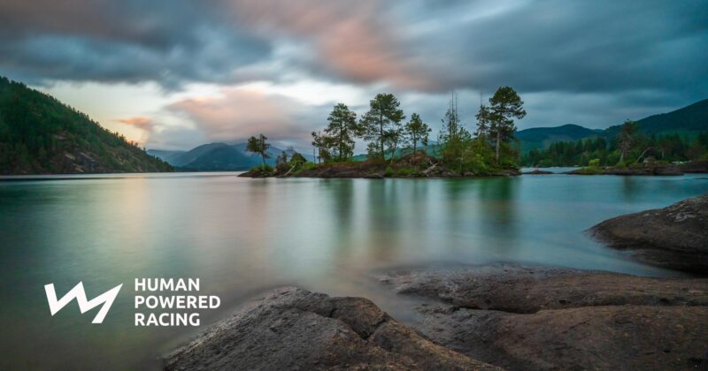 An image of a lake with rocks and trees in the background.