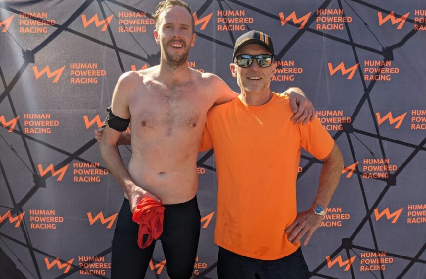Two men standing next to each other at a race.