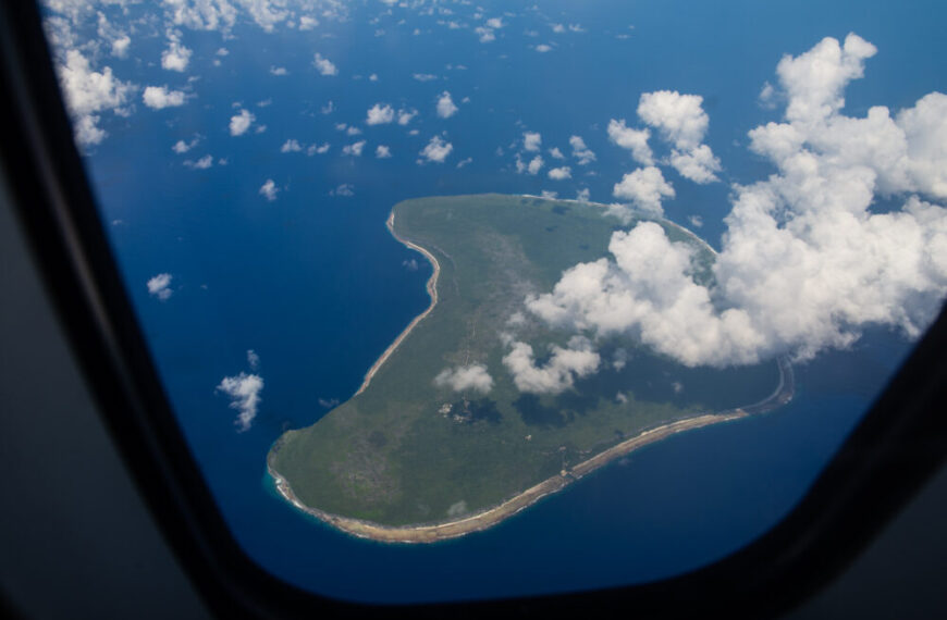 An island is seen through the window of an airplane.