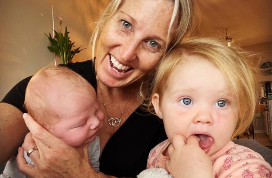 A woman with two small children holding a camera.