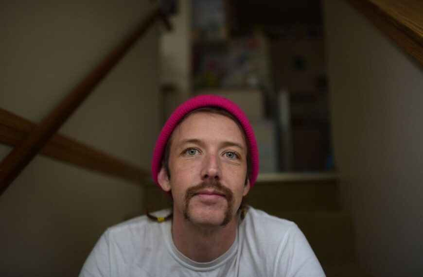A man in a pink hat sitting on stairs.