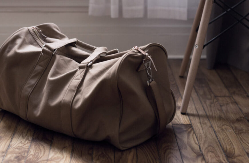 A brown duffel bag sitting on a wooden floor.