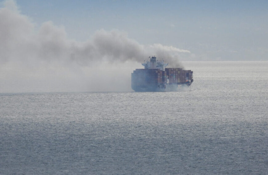 A ship in the ocean with smoke coming out of it.