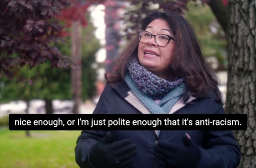 A woman in glasses is talking to a tree.