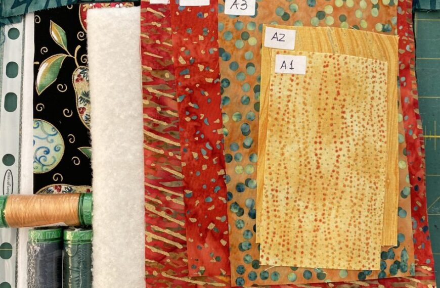 A collection of fabrics and threads on a cutting board.