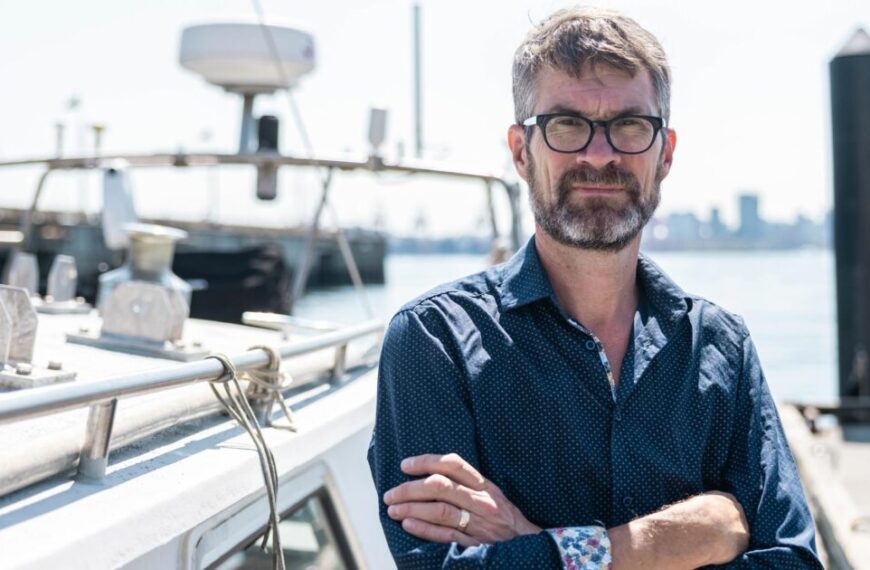 A man standing on a boat with his arms crossed.