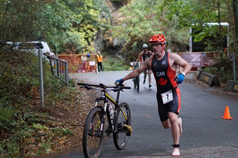 A man is running with his bike in the woods.