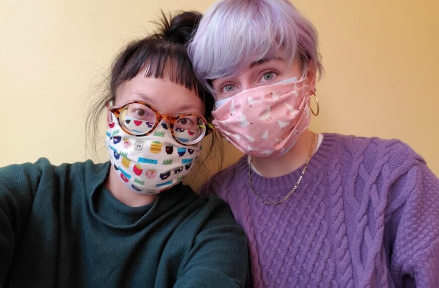Two women posing for a photo wearing face masks.