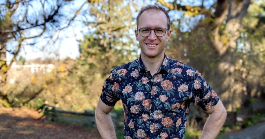A man in a floral shirt standing in a park.
