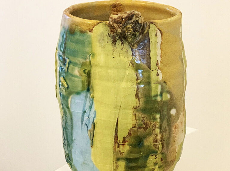 A yellow and green vase sitting on top of a table.