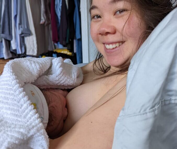 A woman laying in bed with a baby in her arms.