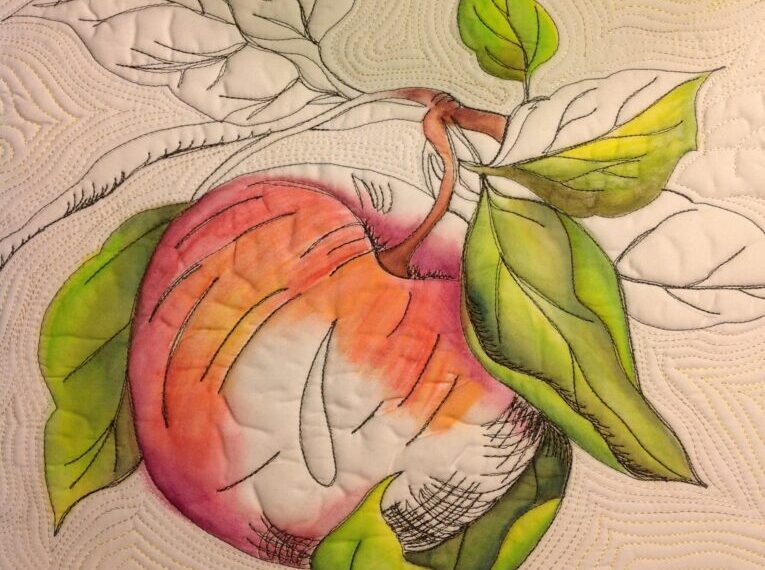 A quilt with an apple and leaves on it.