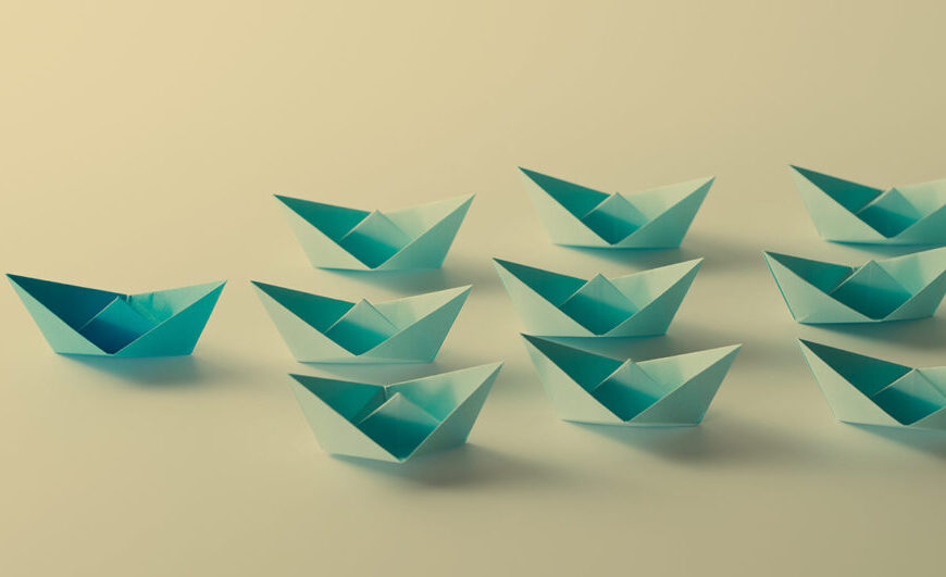 A group of blue origami boats on a beige background.