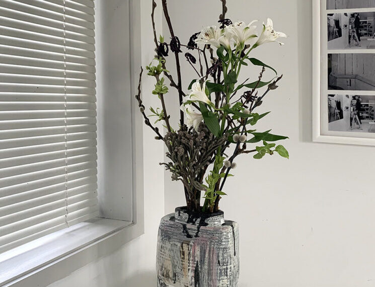 A vase of flowers sitting on a table in front of a window.