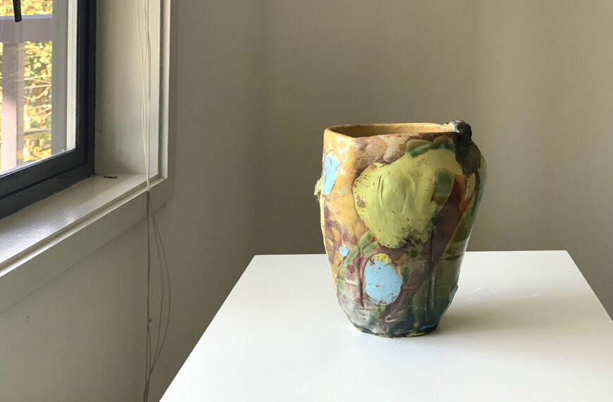 A vase sitting on a table in front of a window.