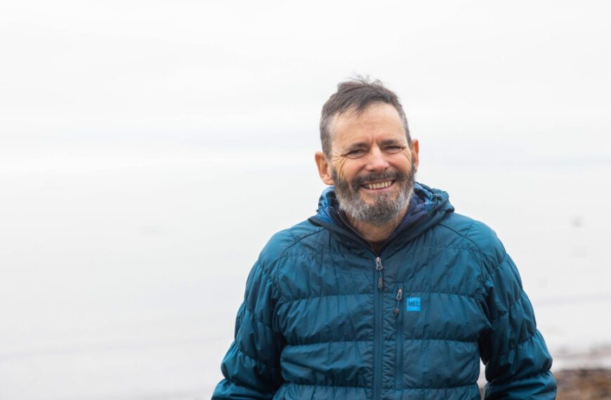 A man in a blue jacket standing on a beach.