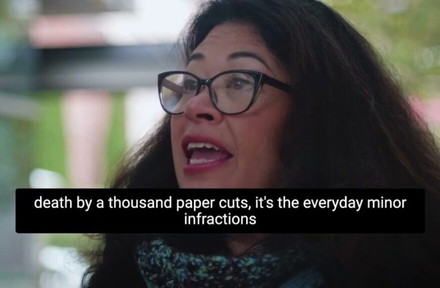 A woman in glasses is talking about the death of a thousand paper cuts.