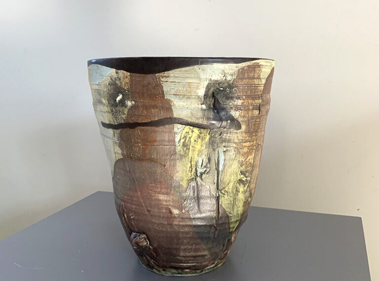 A ceramic vase sitting on a table in a room.