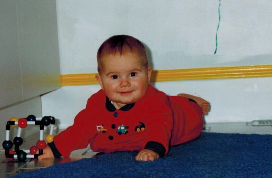 A baby laying on a blue rug.