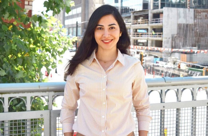 A woman in a tan shirt standing on a bridge.