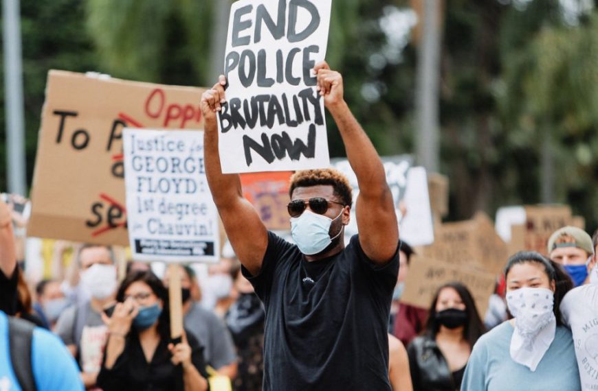 A group of people holding signs and wearing masks.