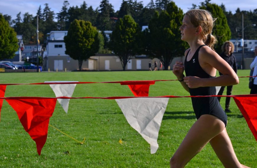 A girl in a swimsuit running on a grassy field.