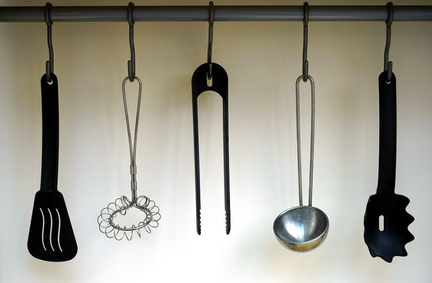 A group of kitchen utensils hanging on a rod.