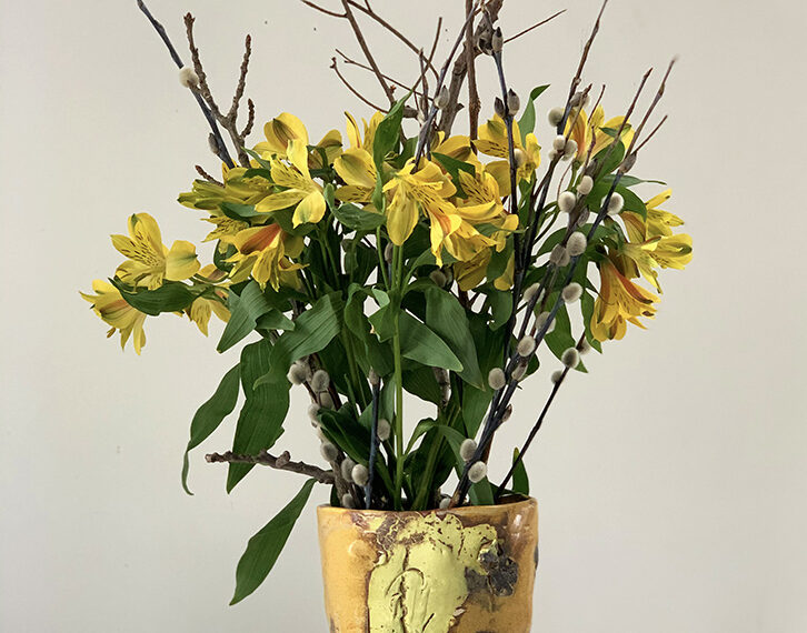 Yellow flowers in a vase on a white table.
