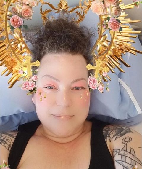 A woman in a bed with a gold crown on her head.