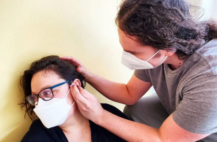 A woman wearing a face mask is being helped by a doctor.