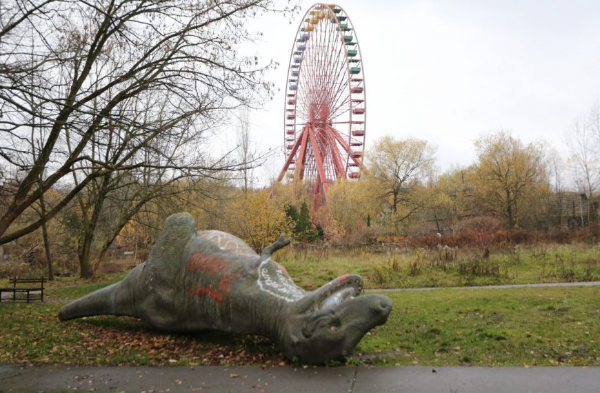A ferris wheel in a park with a statue of a giraffe.