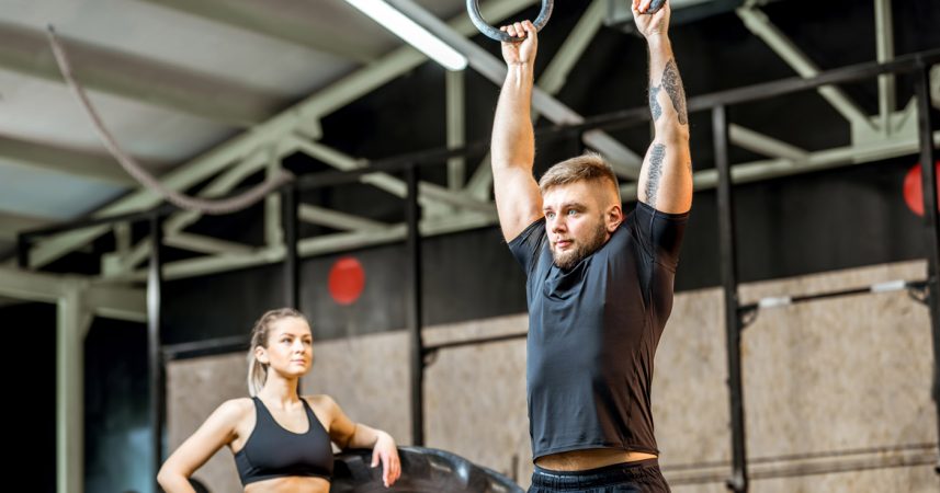 A man and a woman doing crossfit exercises in a gym.