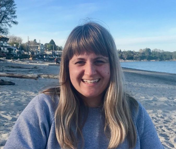 A woman sitting on a beach with a smile on her face.