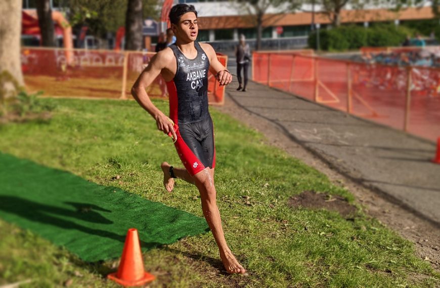 A man running in a triathlon race with cones in the background.
