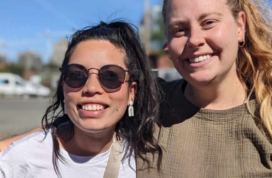 Two women are smiling while standing next to each other.
