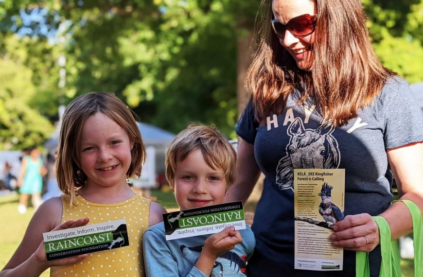 A woman and two children are holding signs at an outdoor event.