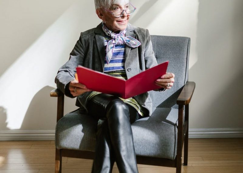 An older woman sitting in a chair reading a book.
