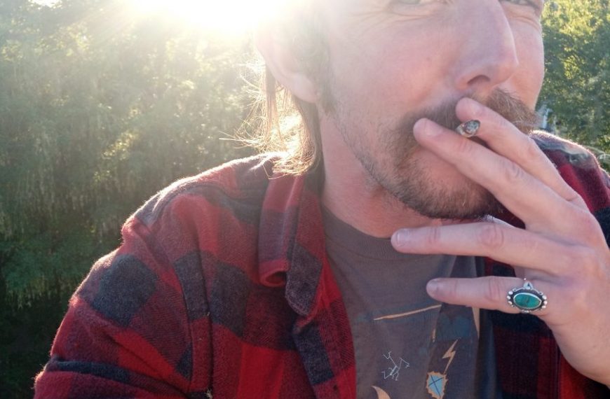 A man with a mustache smoking a cigarette.