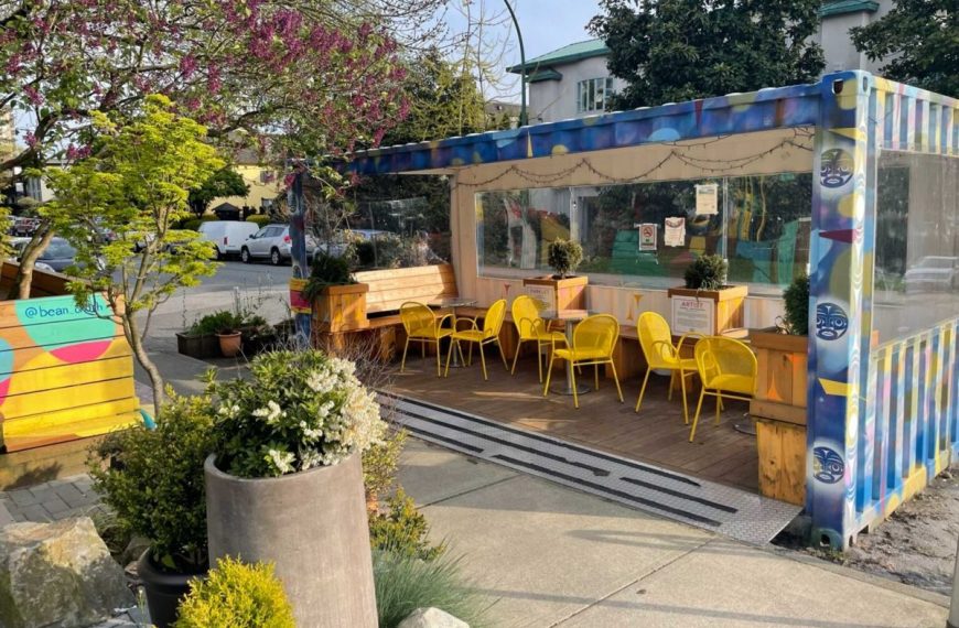 A colorful shipping container with tables and chairs in front of it.