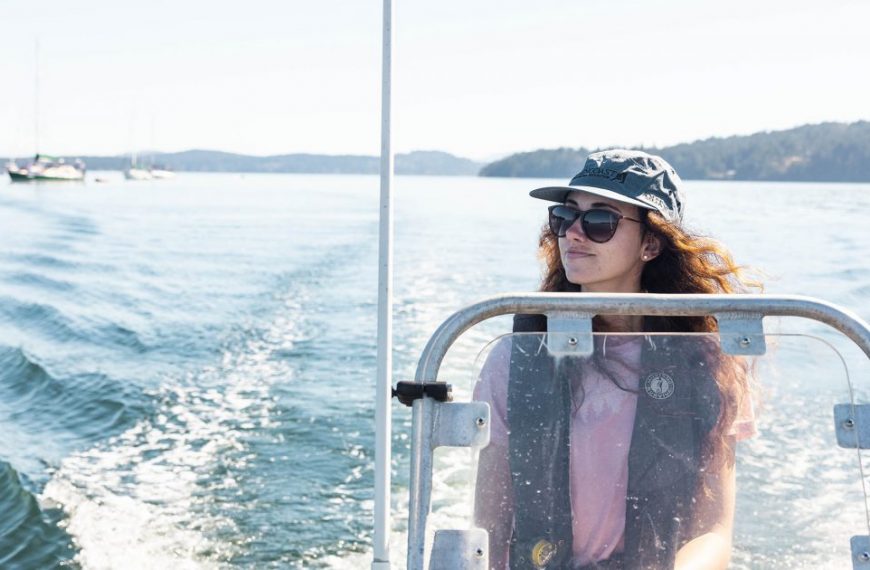 A woman wearing sunglasses and a hat on a boat.