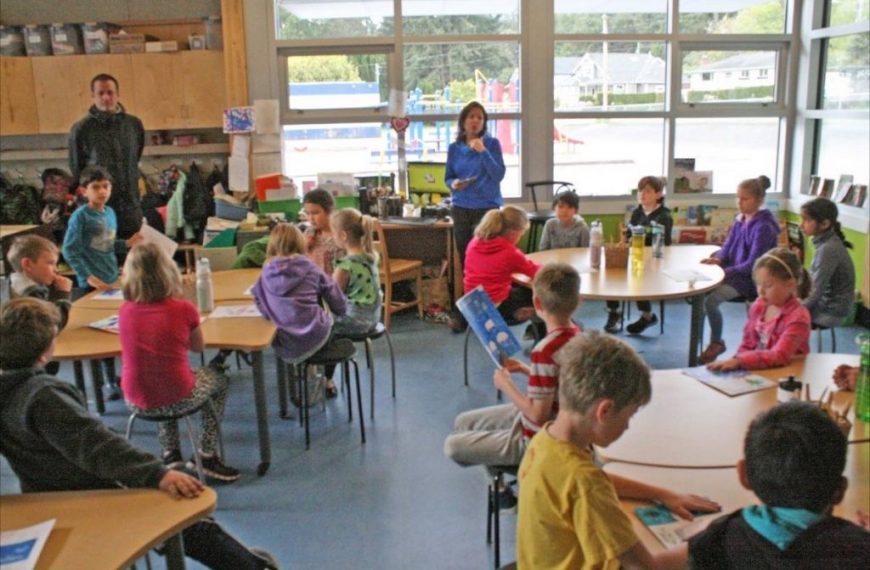 A group of children sitting at tables in a classroom.