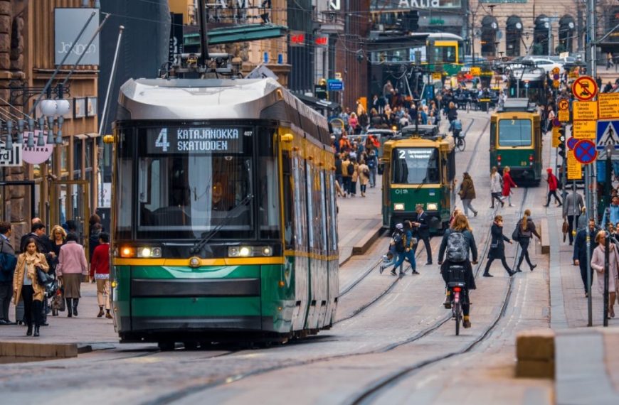 A green tram traveling down a city street.
