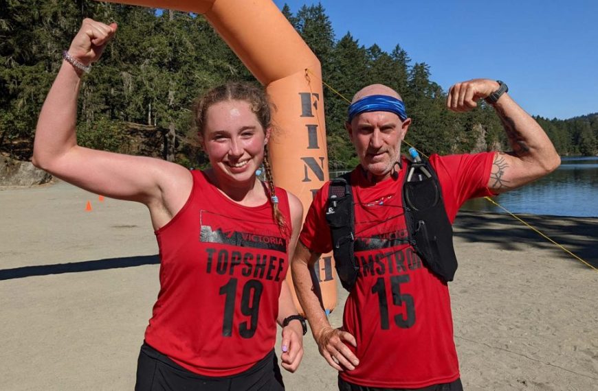 Two people posing in front of a finish line.