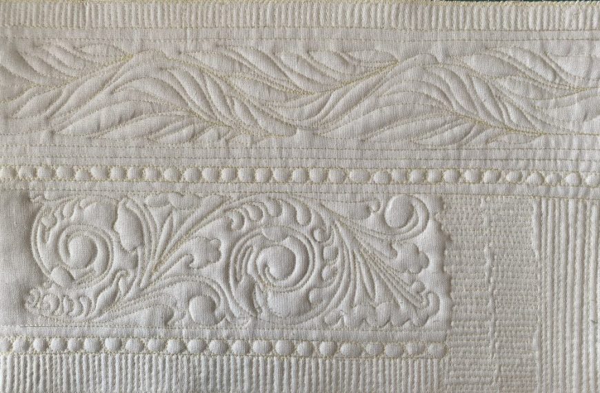 A white quilt with a design on it.