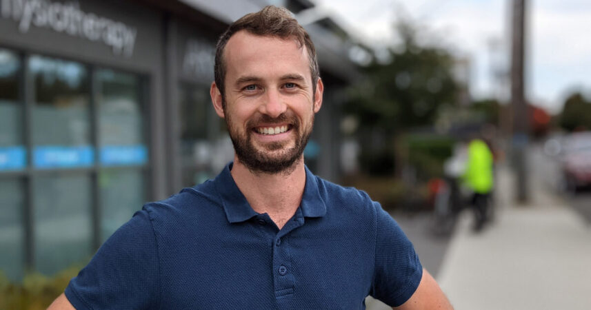 A man smiling in front of a building.