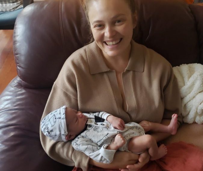 A woman holding a baby on a couch.