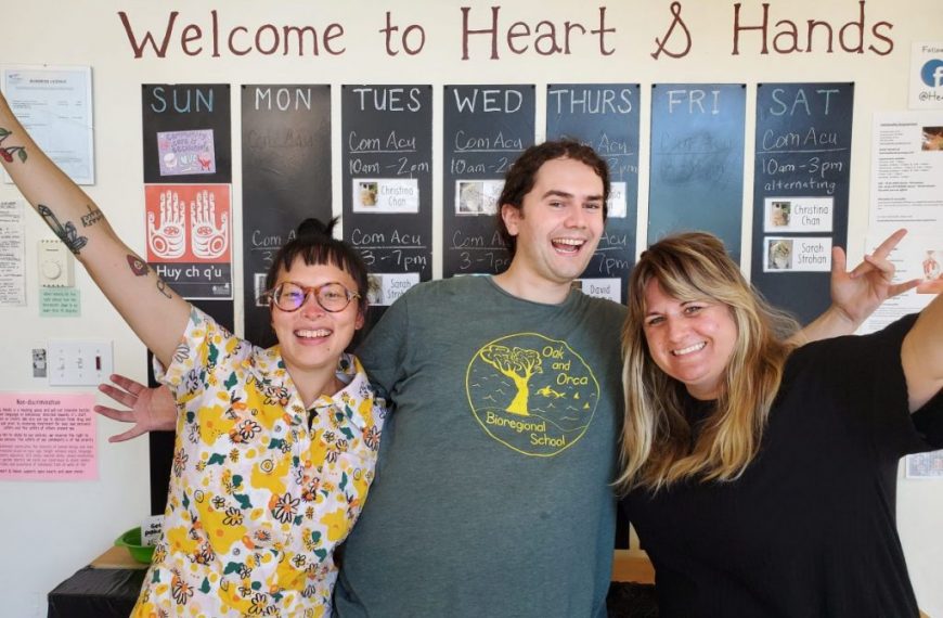 Three people standing in front of a sign that says welcome to heart & hands.