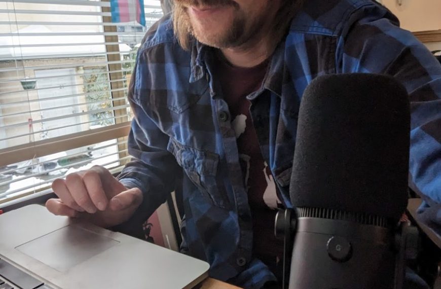 A man with a microphone in front of a laptop.