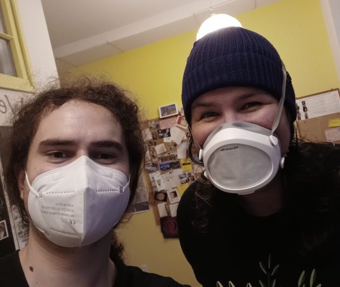 Two people wearing face masks in a room.